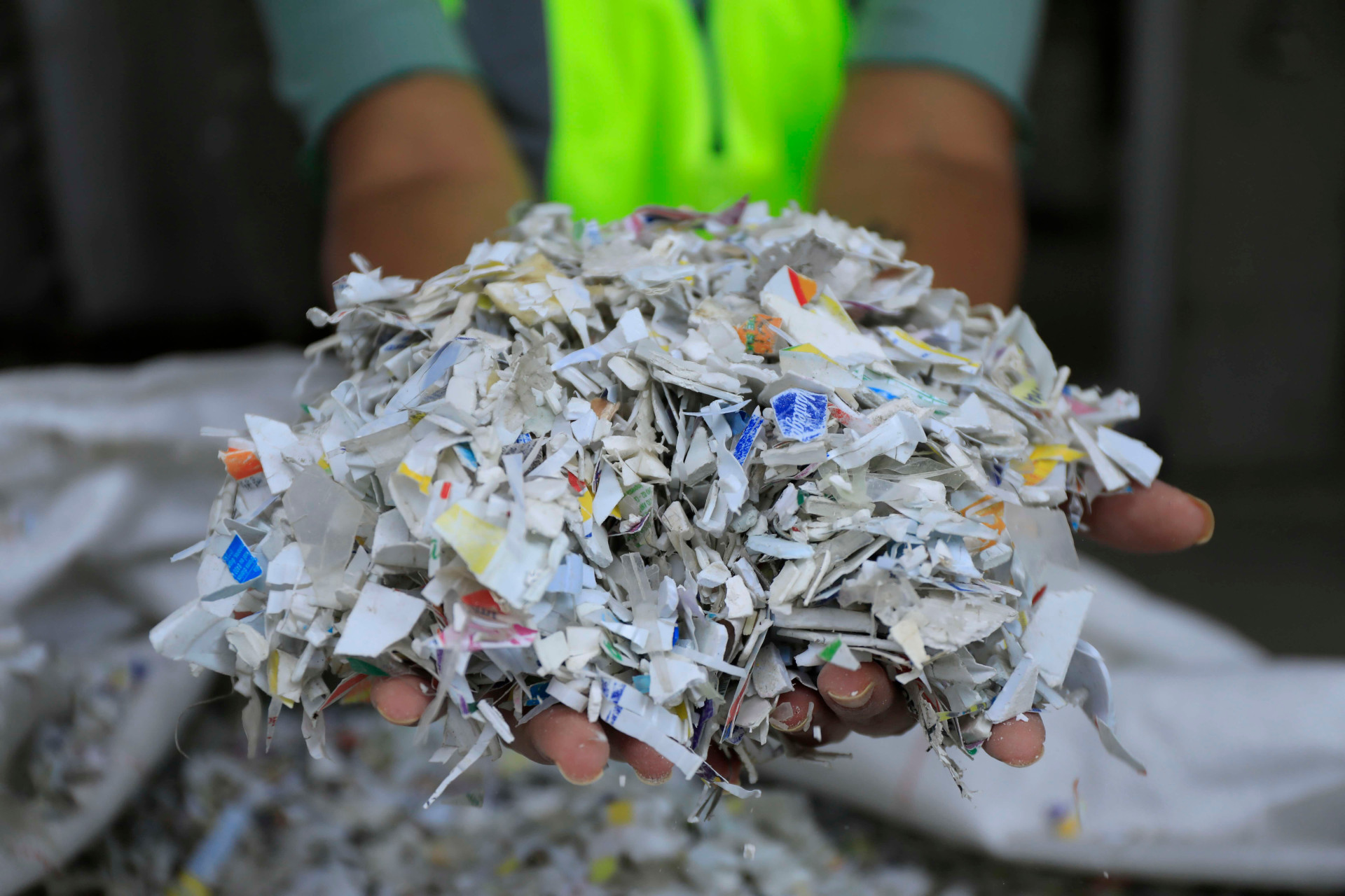 Mãos segurando papel triturado para reciclagem